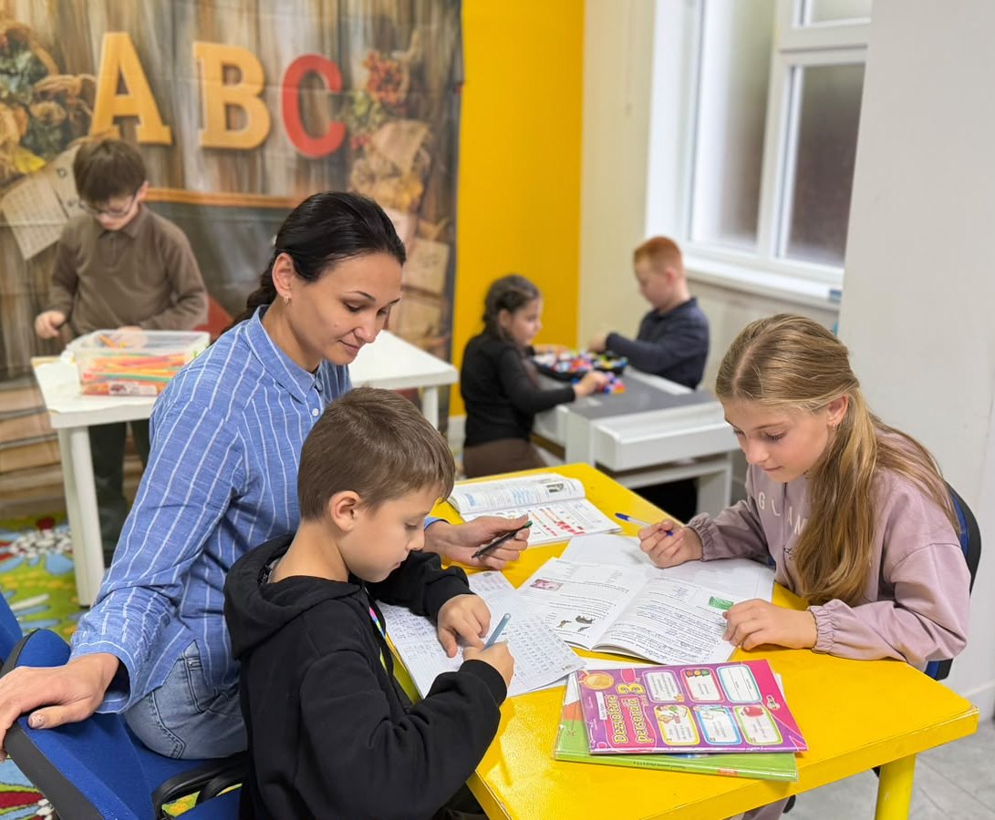 Profesoara ajută copiii la teme în sala de After School