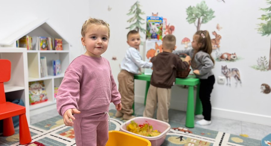 Fetiță zâmbitoare în sala de joacă a creșei și grădiniței