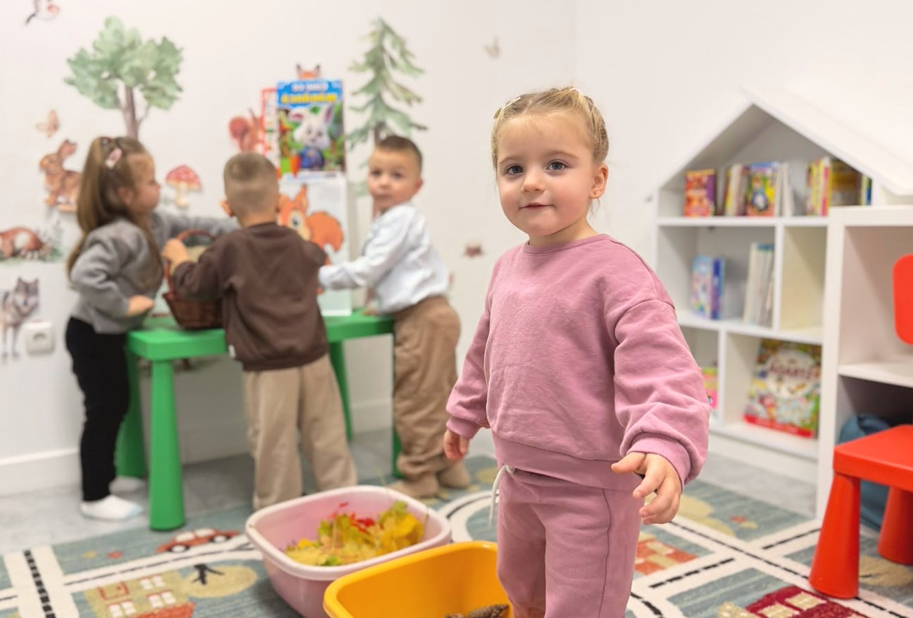 Fetiță zâmbitoare în sala de joacă a Academiei Copiilor