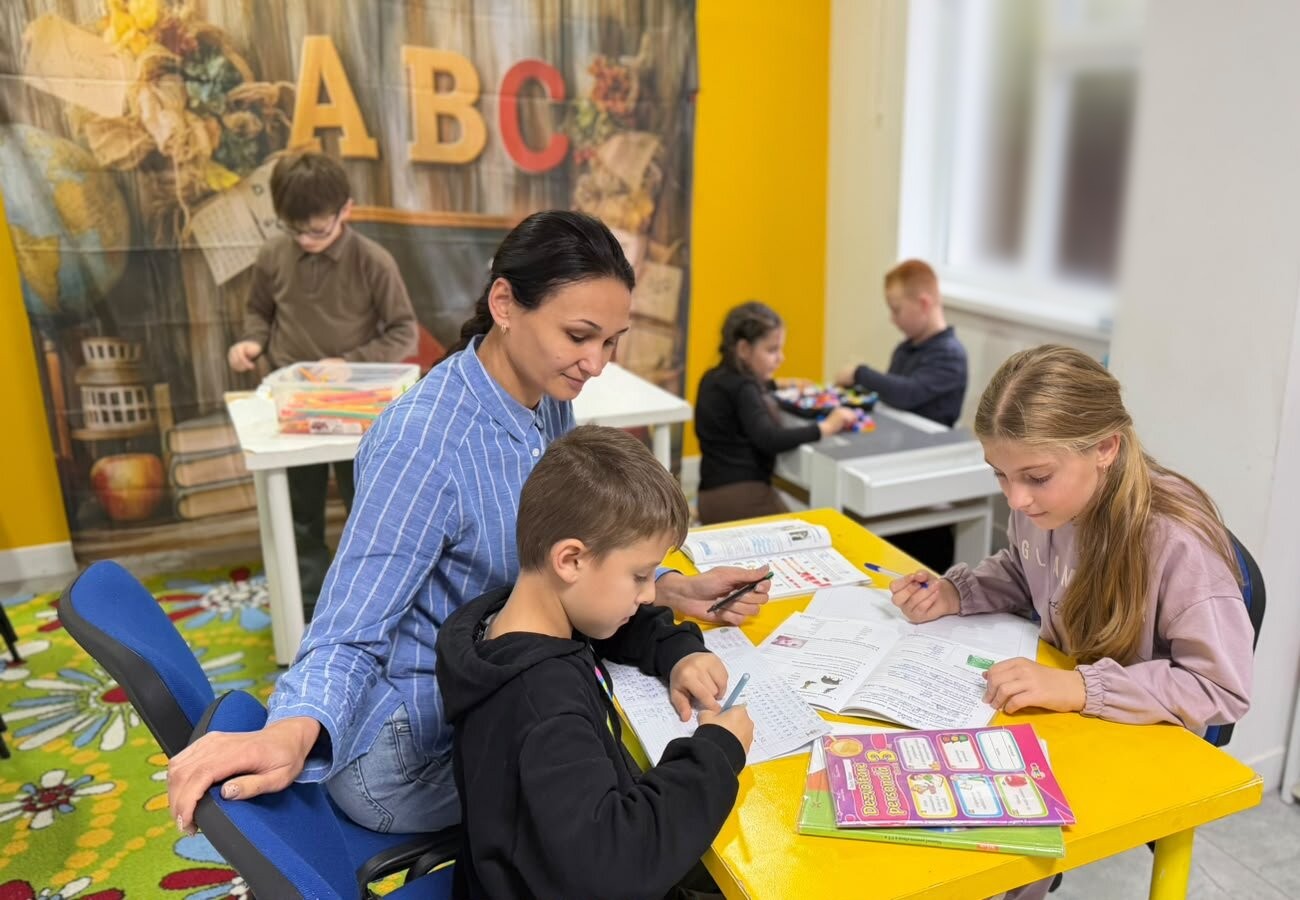 Educatoarea lucrează cu copiii la masa galbenă, la Academia Copiilor