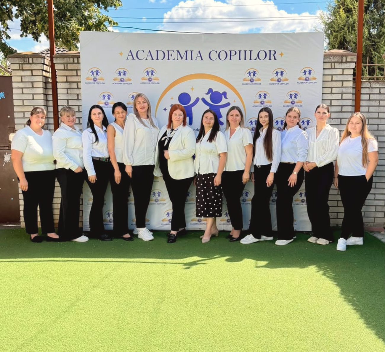 Echipa Academiei Copiilor în fața panoului cu logo-ul Academiei