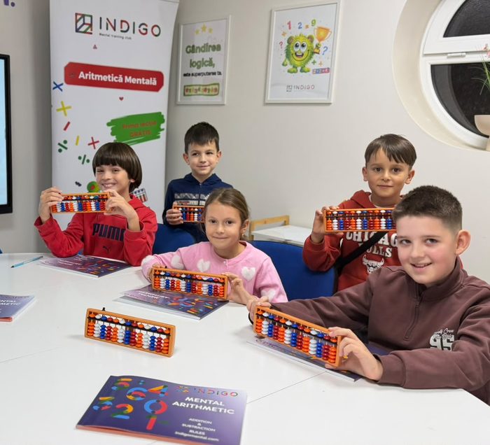 Copii zâmbitori care țin abacul la cursul de Aritmetică Mentală Indigo