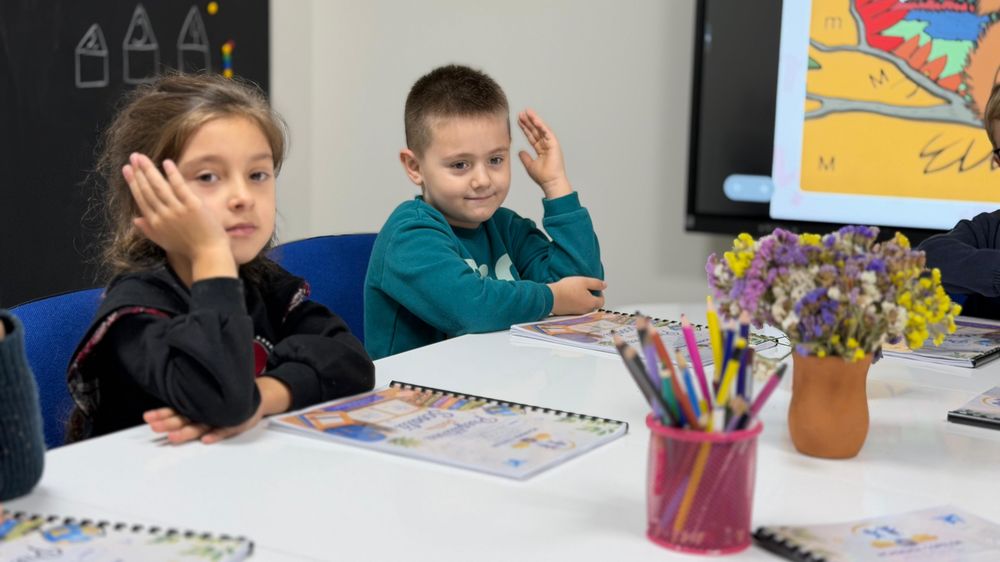 Băiețel care ridică mâna la lecție
